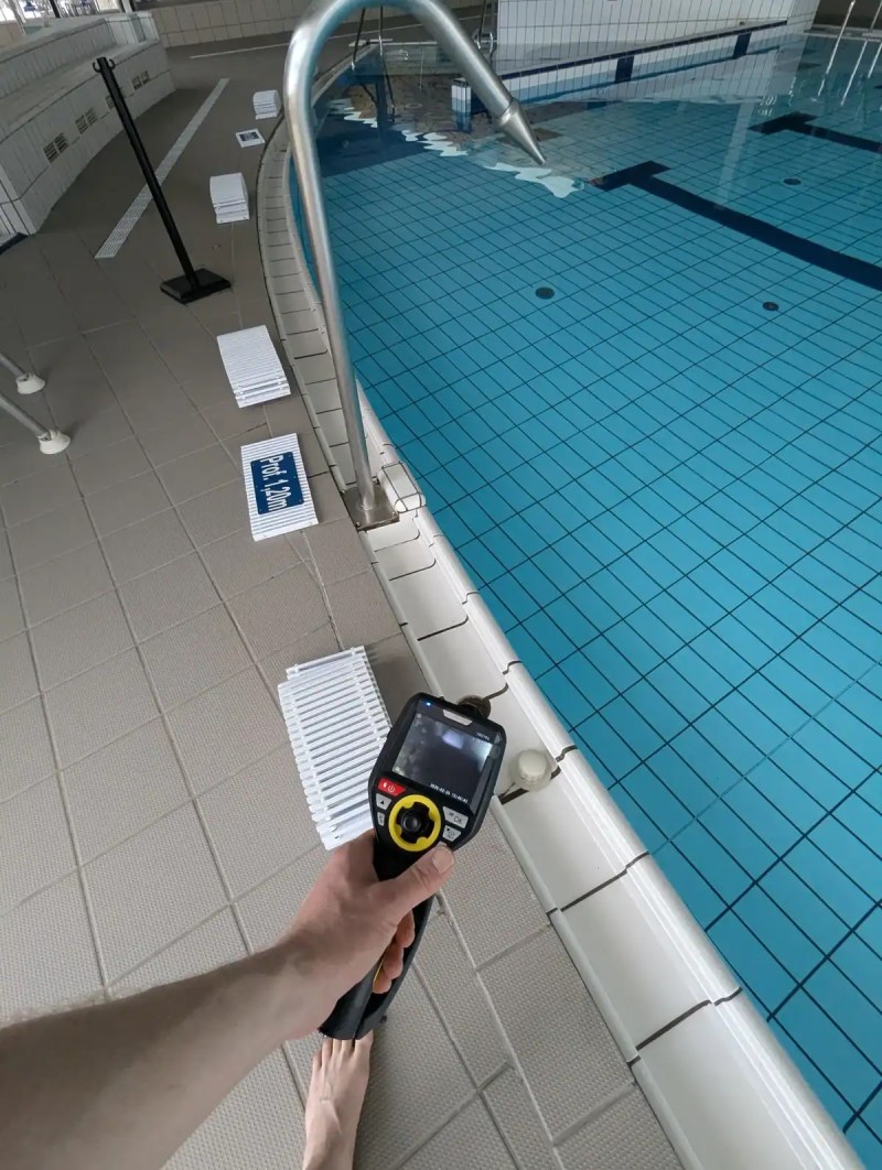 Technicien tenant une caméra d’inspection au bord d’un bassin intérieur carrelé
