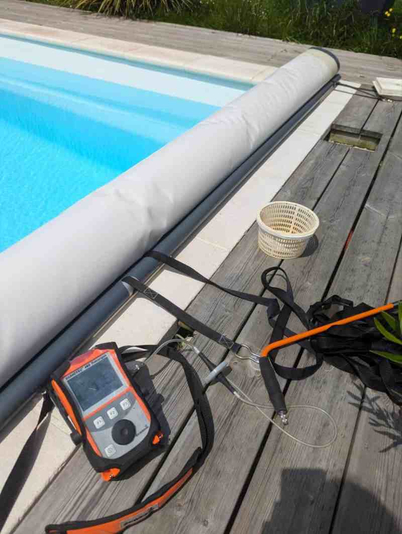 Détecteur de gaz traceur sur son harnais au bord d’une piscine de jardin à volet roulant