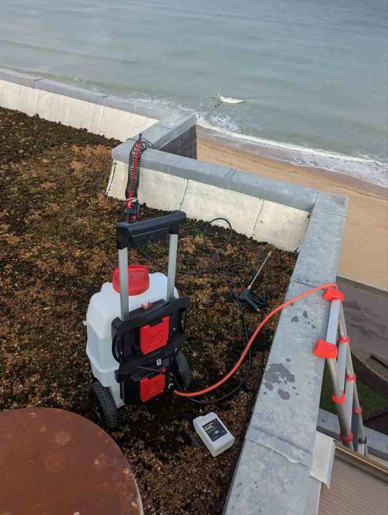 Toit-terrasse au-dessus de la plage : pulvérisateur, tuyaux et échelle télescopique installés pour un test d’arrosage